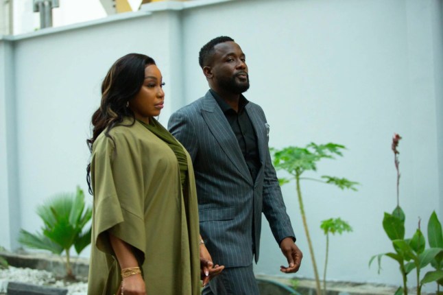 A still from baby Farm of a woman in green clothing and a man in a suit